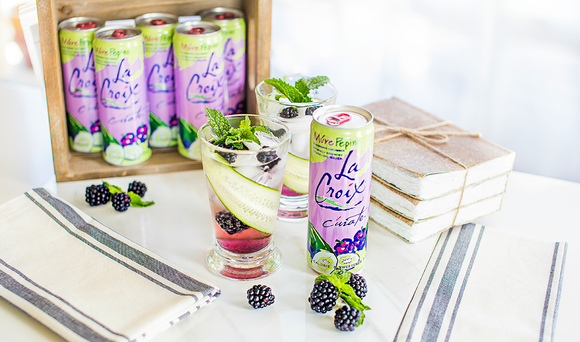 Display of La Croix Pepino flavor cans along with a glass with fruit in it.