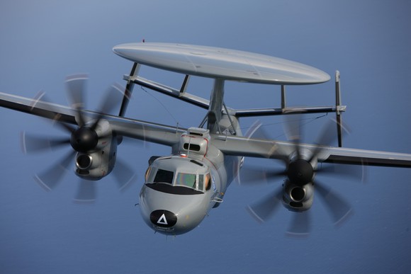 E-2 Hawkeye aircraft, airborne against a blue sky.