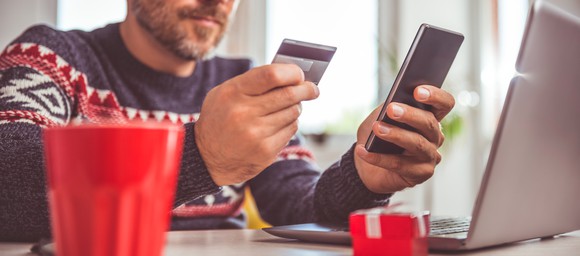 Man shopping on smartphone with credit card in hand.