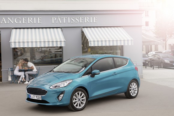 A green 2018 Ford Fiesta hatchback with European license plates is shown parked in front of a bakery in France.
