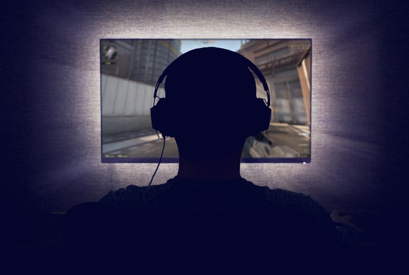 The silhouette of a person playing a video game in a dark room.