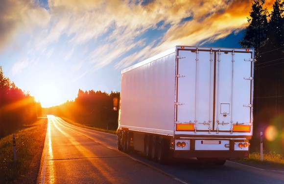 Tractor trailer driving into sunrise