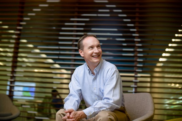 David Gardner smiling over his shoulder while sitting.