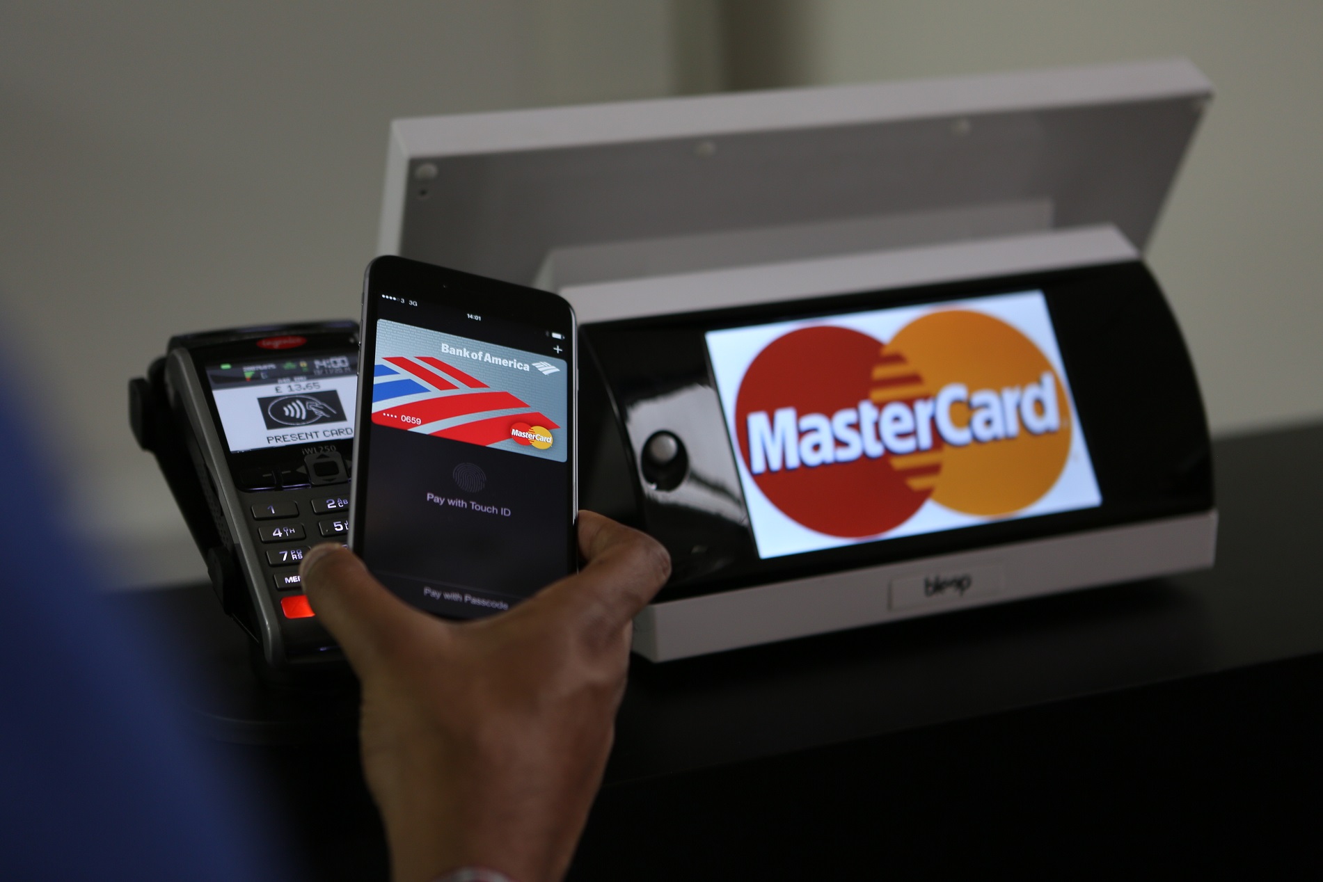 Card reader showing Mastercard logo with a mobile device on top of it.