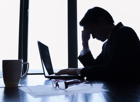 Business man looking worried in front of laptop.