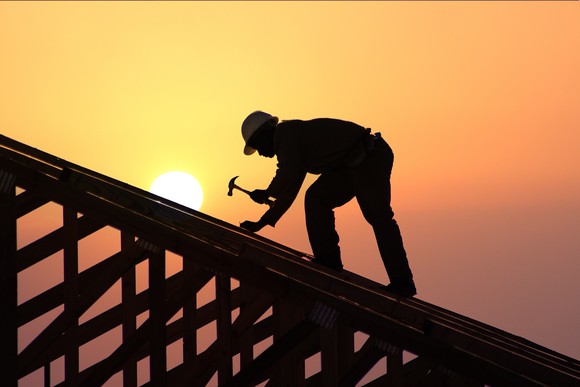 A builder working on the roof of a new home under construction