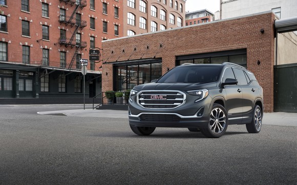 A black GMC Terrain crossover SUV, parked in front of a brick building.