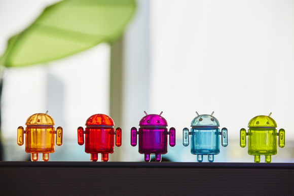 Five plastic toy versions of Alphabet's Android robot lined up in a row.