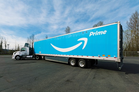 Semi truck pulling a sky-blue trailer, which features the smiling Amazon Prime logo in white.