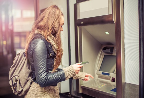 A woman prepares to enter her card into an ATM.