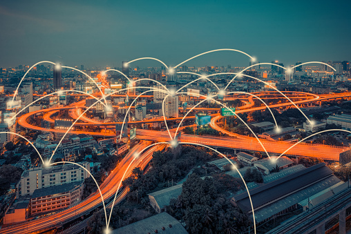 A large city's cloverleaf freeway at night, digitally enhanced and lit up with multiple connectivity points.