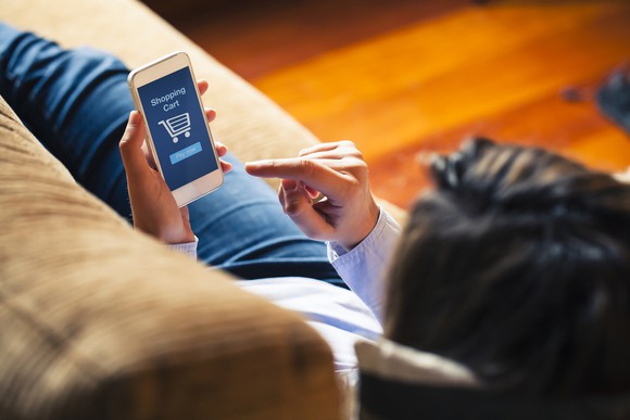 A person shopping on their phone while lying on a couch.