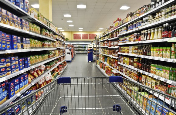 A shopping cart in the middle of a grocery aisle