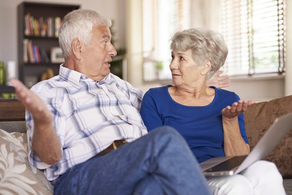 Senior couple looking at a laptop while raising their hands in confusion