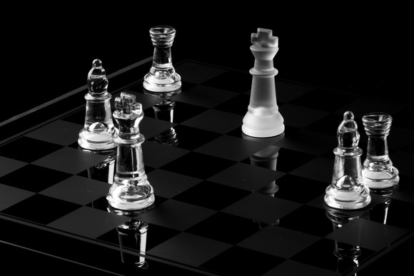 A lone king piece gets surrounded by enemy pieces on a chess board.