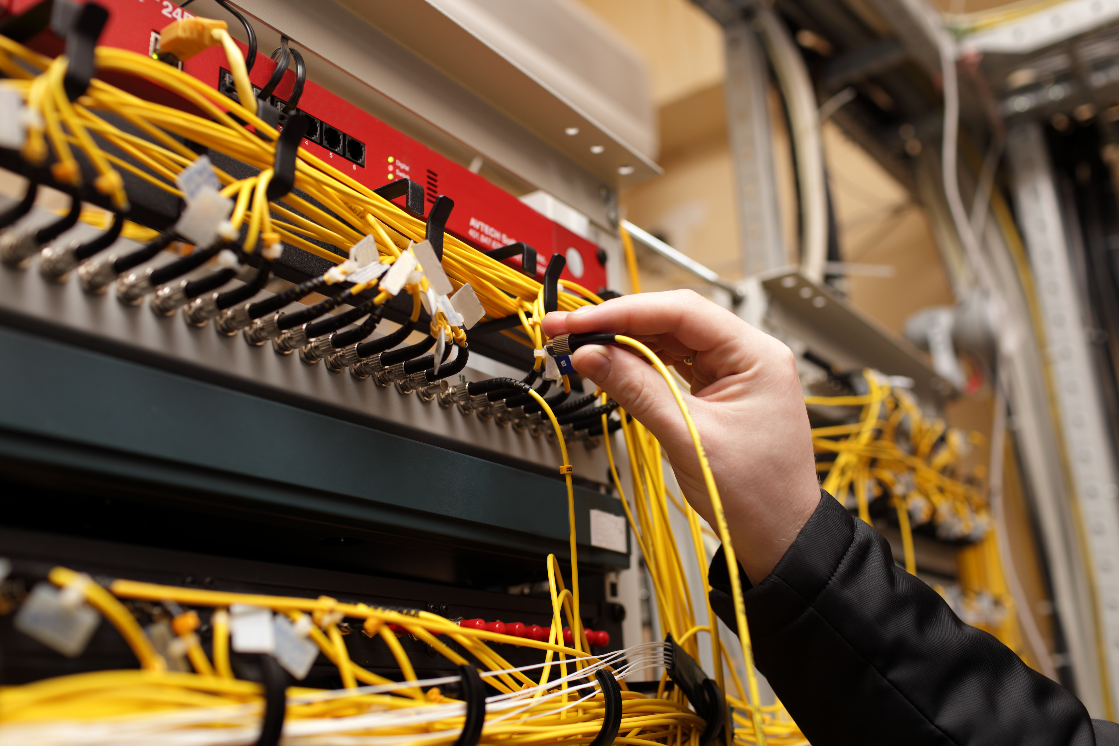 A technician plugs fiber-optic network cables into a high-speed switch.