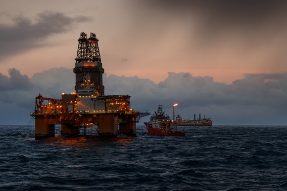 Offshore oil rig and support ship at sea.