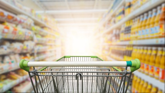 A shopping cart going down an aisle at a grocery store