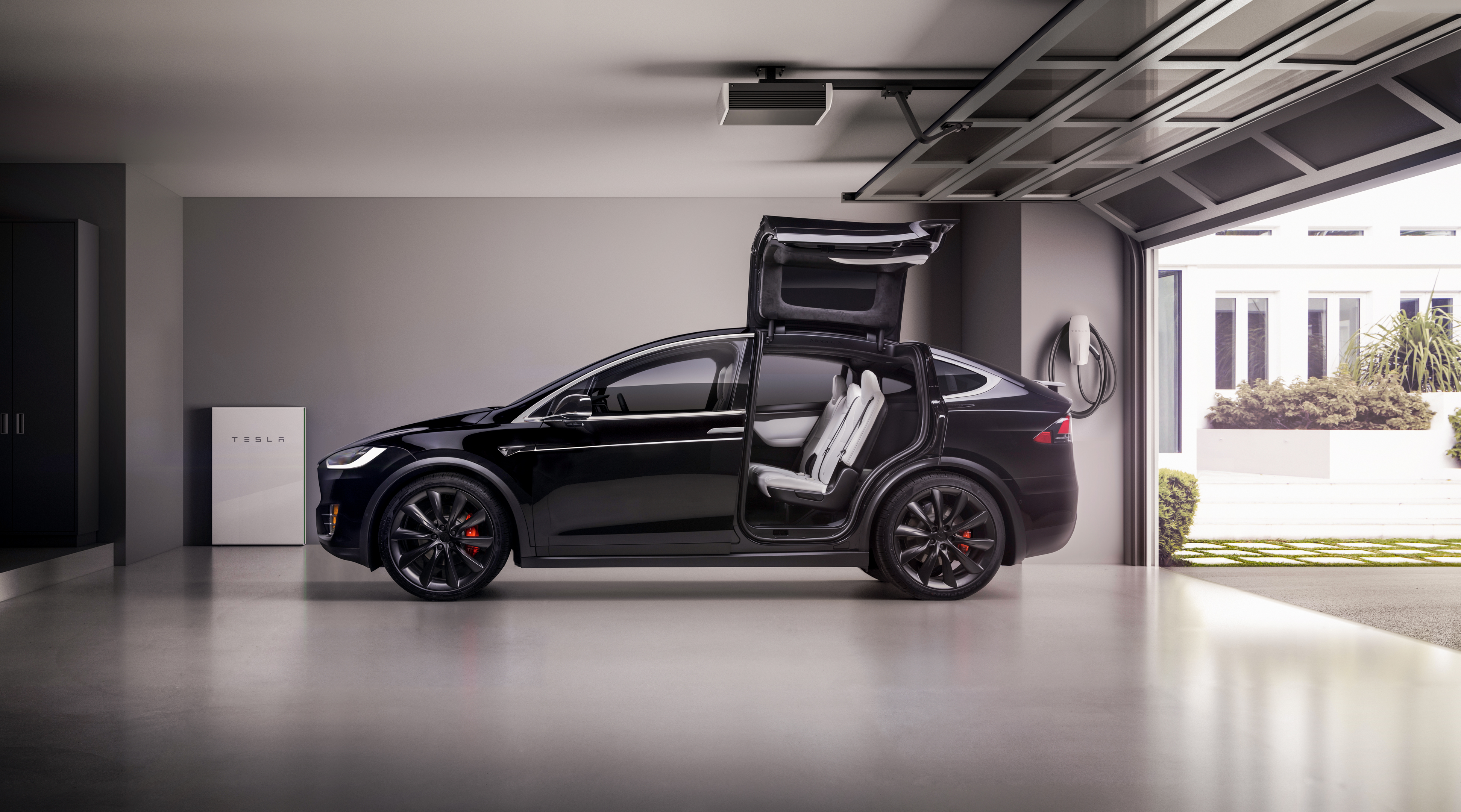 A Tesla Model X with its falcon wing doors open in a garage