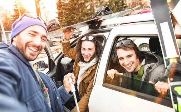 A group of friends holding skiing equipment while on vacation.