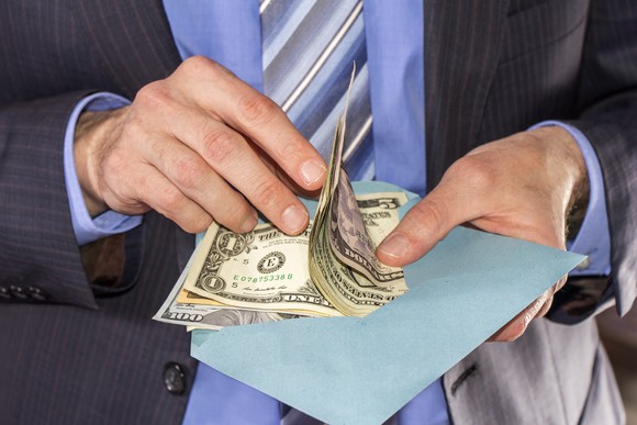 Man in suit counting bills from an open envelope