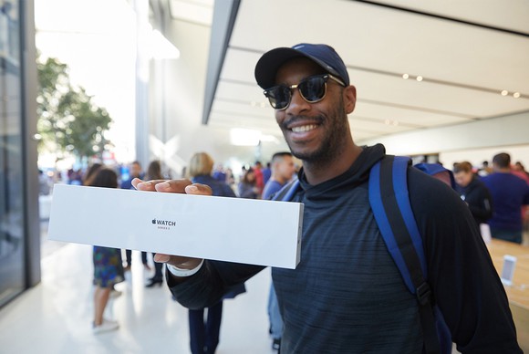 An excited customer holds an Apple Watch 3 Series in a box at an Apple Store.