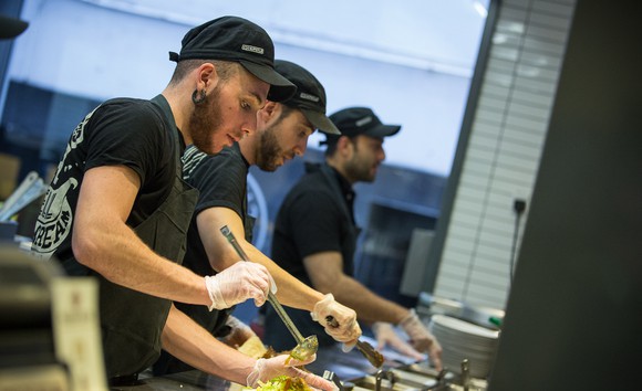 Chipotle workers assemble food.