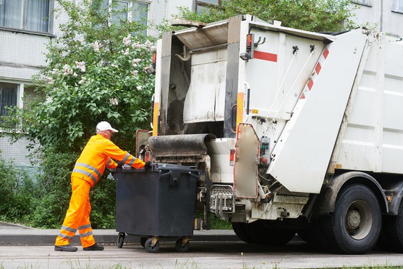 Garbage worker and bin outside a garbage truck