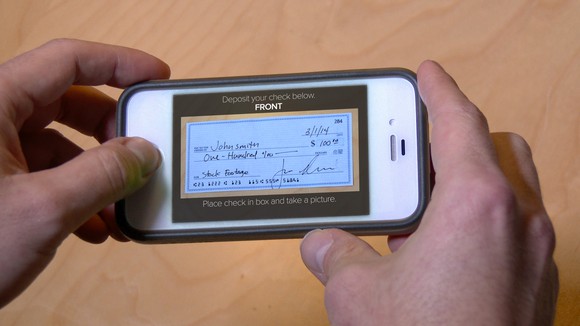 A person using a mobile phone to deposit a check into his bank account.