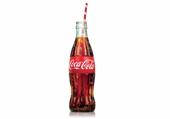 An uncapped Coke bottle with a red-and-white straw inside.