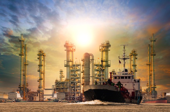 An oil refinery with a bright sun in the background.