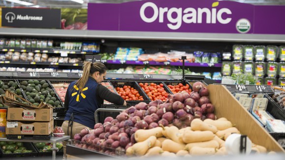 A Walmart employee stocks items in the produce section.