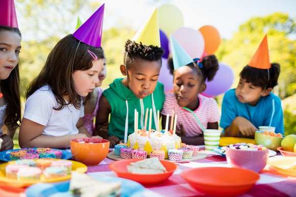 Children watching a boy blow out birthday candles