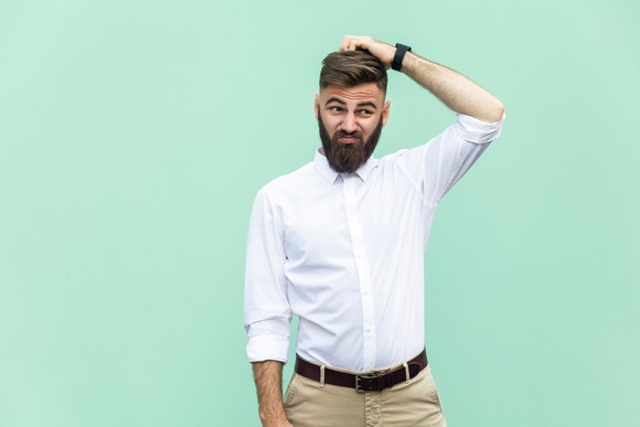Man with beard scratching his head.