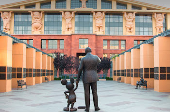 A bronze statue of Walt Disney holding hands with Mickey Mouse.