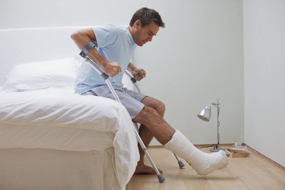 Man with leg cast getting out of bed
