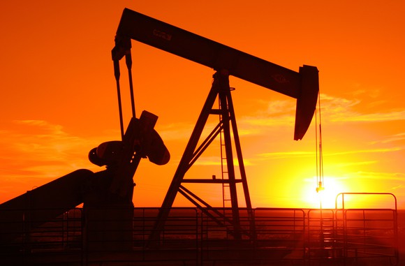 A pump jack with an orange sunset
