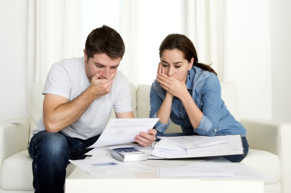 Couple covering their mouths while looking at papers