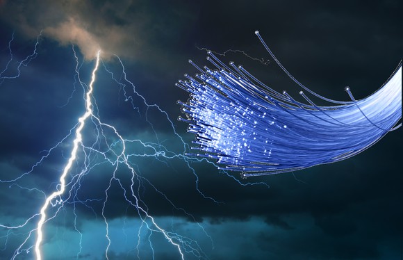 A bundle of fiber-optic cables in front of stormy skies and a lightning bolt.