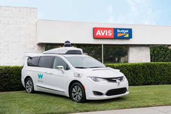 Waymo vehicle with autonomous technology parked in front of an Avis store