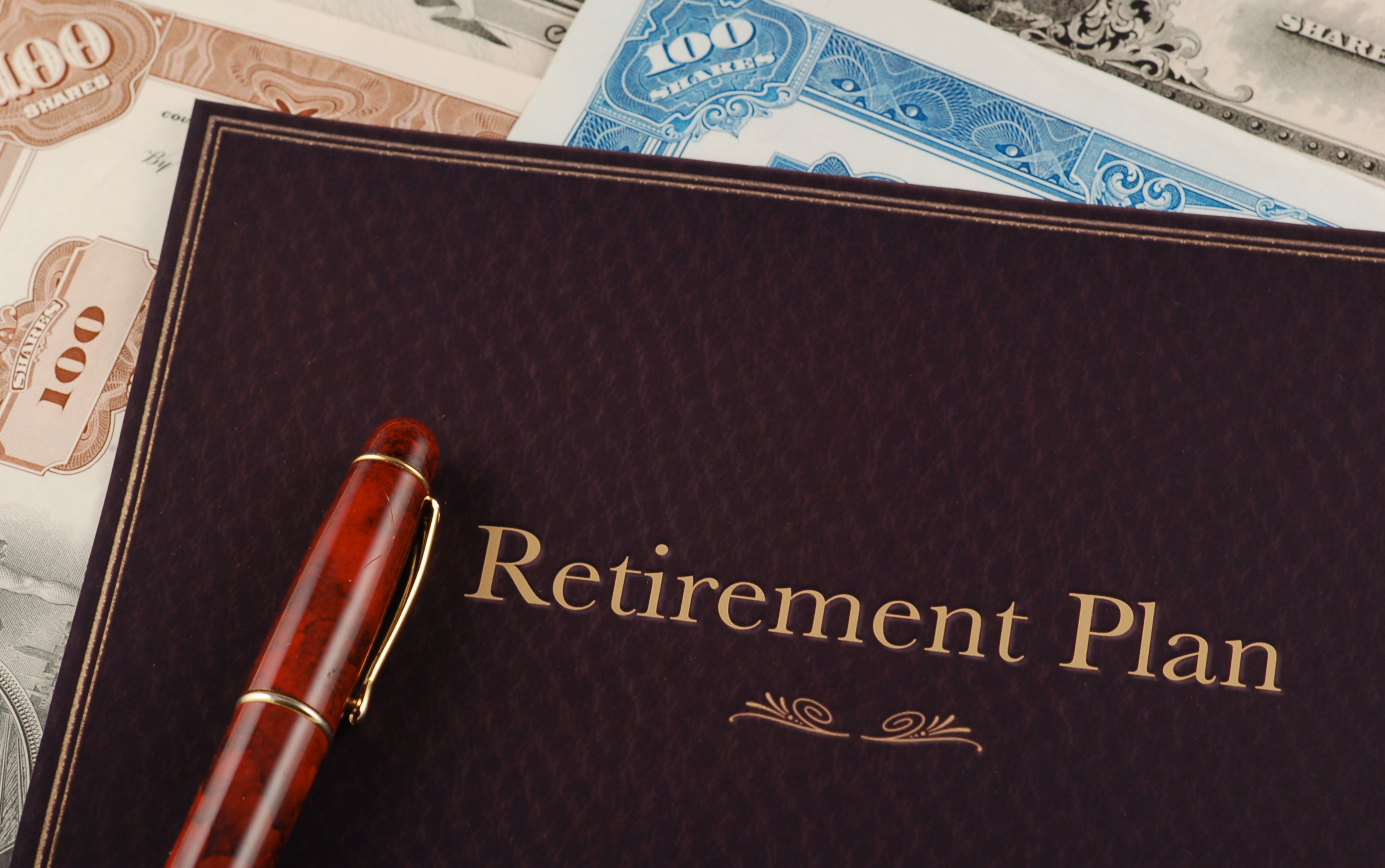 Retirement plan portfolio on top of stock certificates.