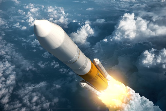 Rocket launching through air with clouds in the background