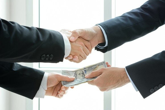 Two men exchange a handshake and money.