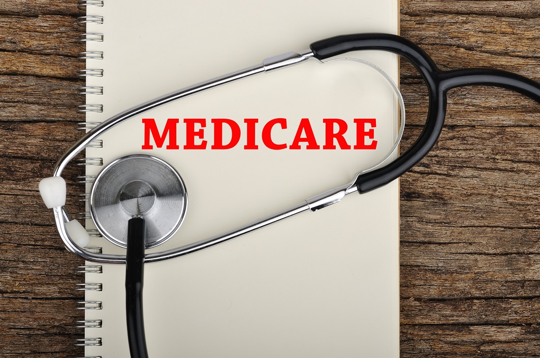 Notebook labeled Medicare on a wood desk with a stethoscope on top.