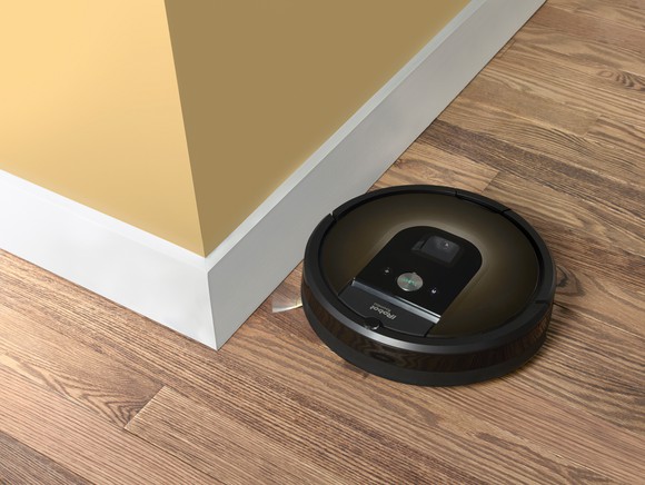 An iRobot Roomba vacuum bot on a wood floor.