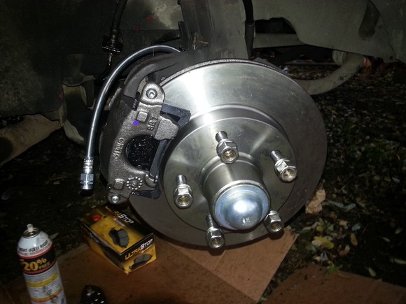 Rotor brake assembly with box of brake pads and a bottle of solvent next to the part.