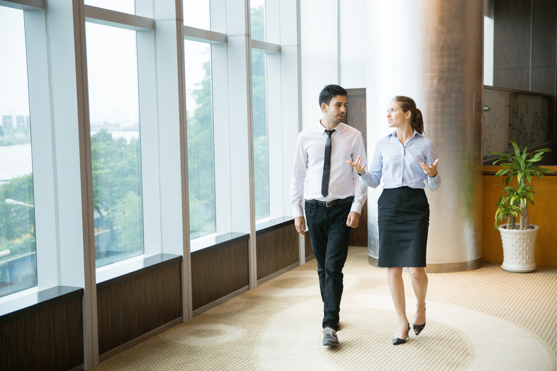 Professional man and woman walking and talking in an office.