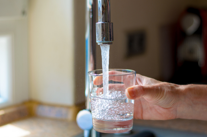 A hand filling up a glass of water.