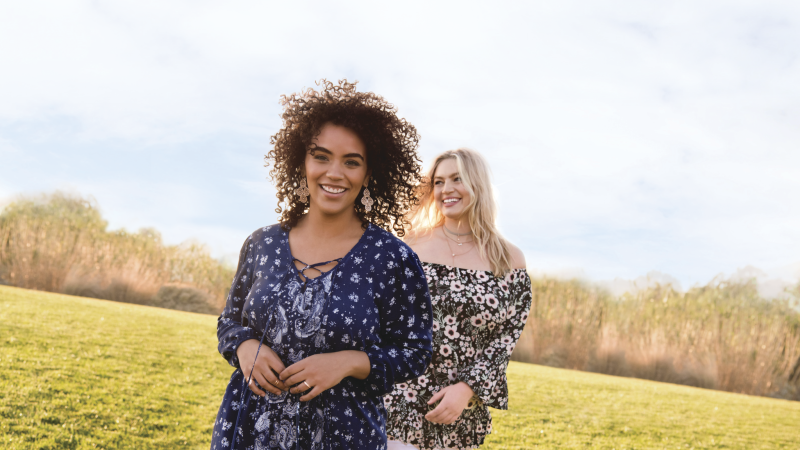 Two smiling women standing in a field