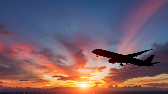 Black silhouette of a passenger airplane flying in a colorful sunset.